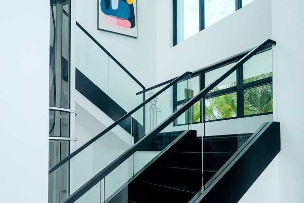 Modern staircase with abstract art and glass railing.