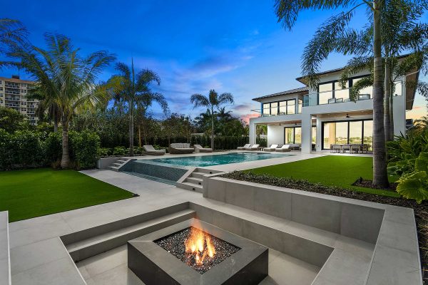 Modern house with pool and fire pit at sunset.