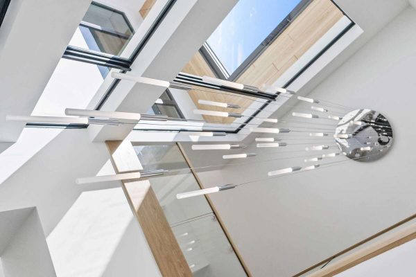 Modern chandelier beneath skylight with geometric design.