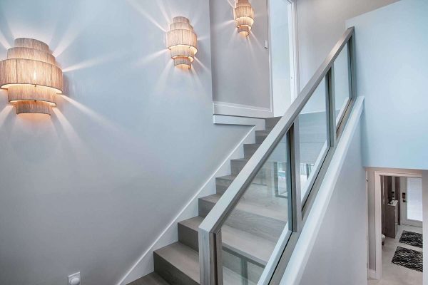 Modern staircase with glass railing and wall sconces