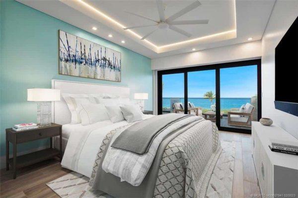 Modern bedroom with ocean view and balcony seating.