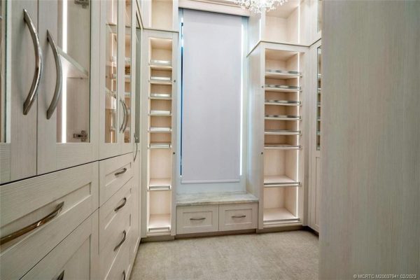 Spacious walk-in closet with white cabinetry and shelves.