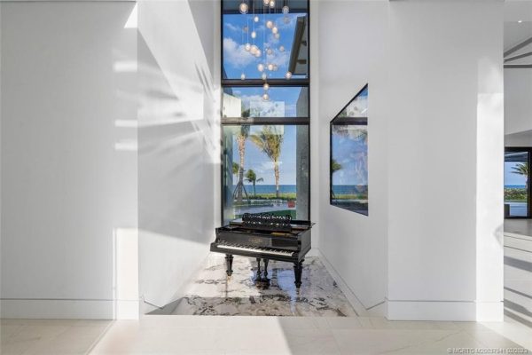 Grand piano in bright ocean-view hallway.