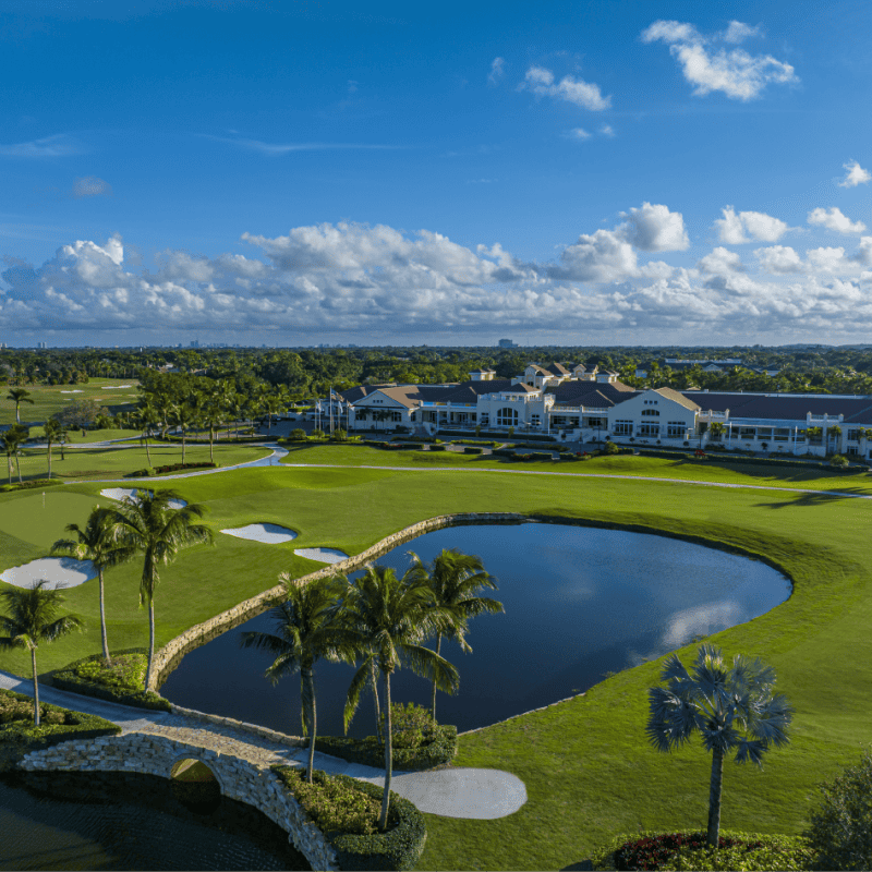 Golf course landscape with clubhouse and pond view.