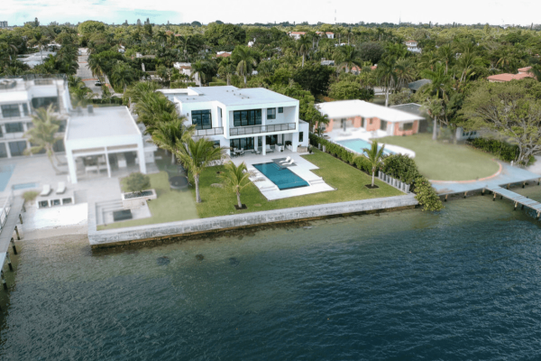 Luxury waterfront home with pool and palm trees.
