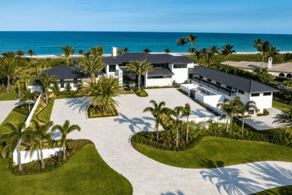 Luxury beachfront mansion with palm trees and ocean view.
