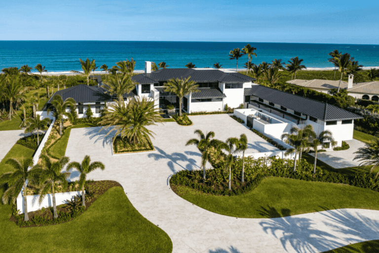 Luxury beachfront mansion with palm trees and ocean view.